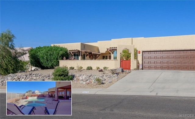 pueblo-style home featuring concrete driveway, an attached garage, and stucco siding