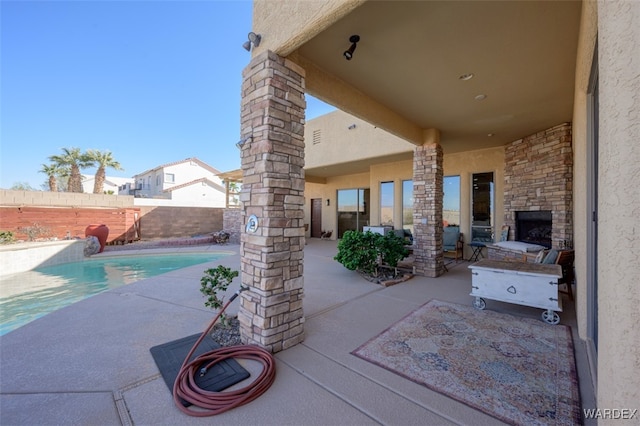 view of patio featuring an outdoor stone fireplace, a fenced backyard, and a fenced in pool