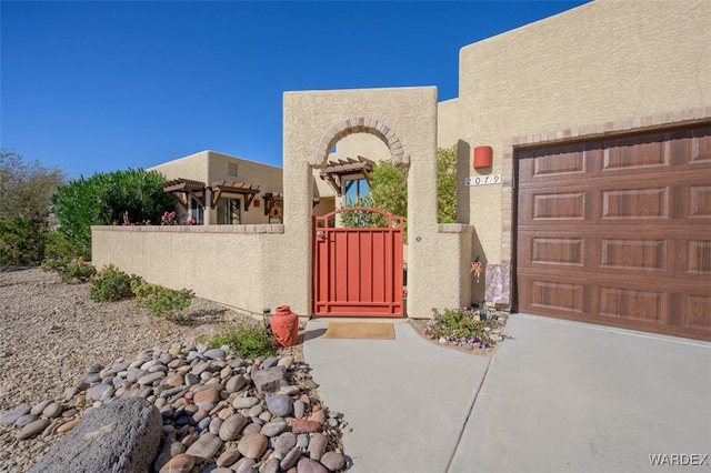 view of exterior entry with fence, a gate, and stucco siding