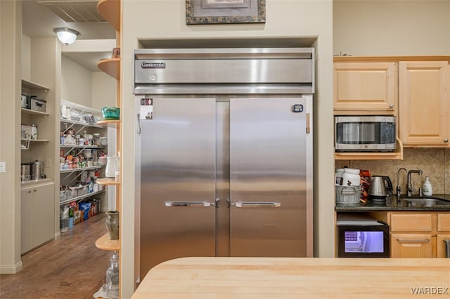 kitchen with dark wood-style flooring, decorative backsplash, light brown cabinetry, appliances with stainless steel finishes, and a sink