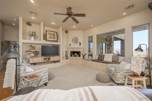 carpeted living room with ceiling fan, a fireplace, visible vents, and recessed lighting