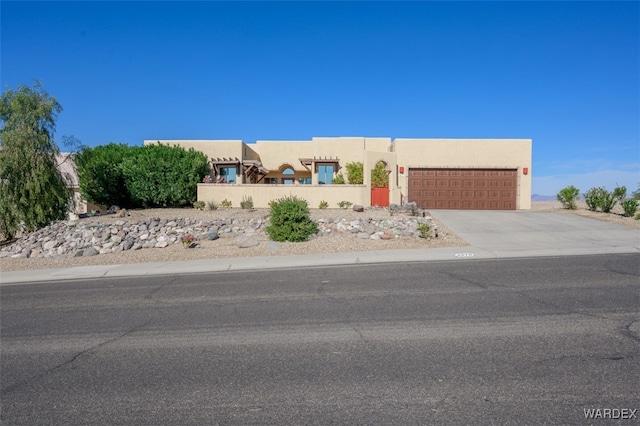 adobe home with driveway, an attached garage, and stucco siding