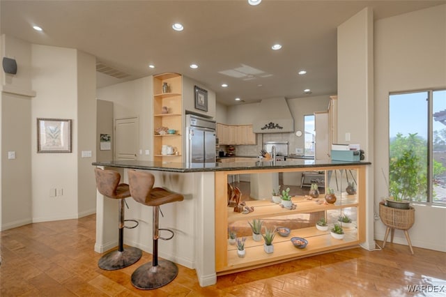 kitchen with premium range hood, a peninsula, built in fridge, and open shelves