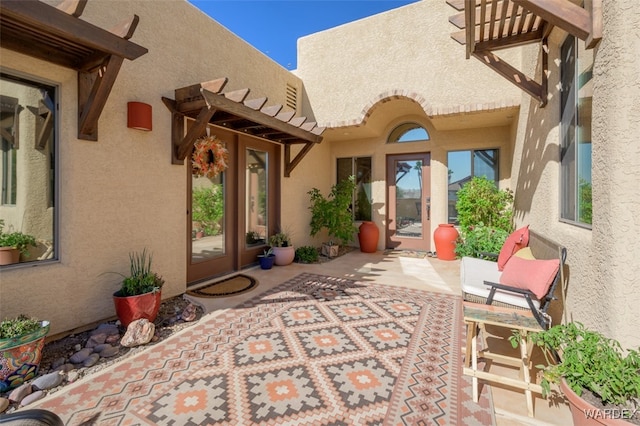 view of exterior entry with a patio and stucco siding