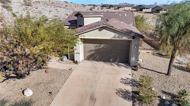 view of front facade featuring stucco siding, concrete driveway, an attached garage, fence, and a tiled roof