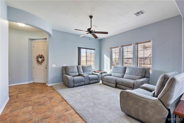 living room featuring arched walkways, visible vents, ceiling fan, and baseboards