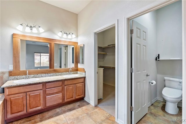 full bathroom featuring a sink, toilet, and double vanity