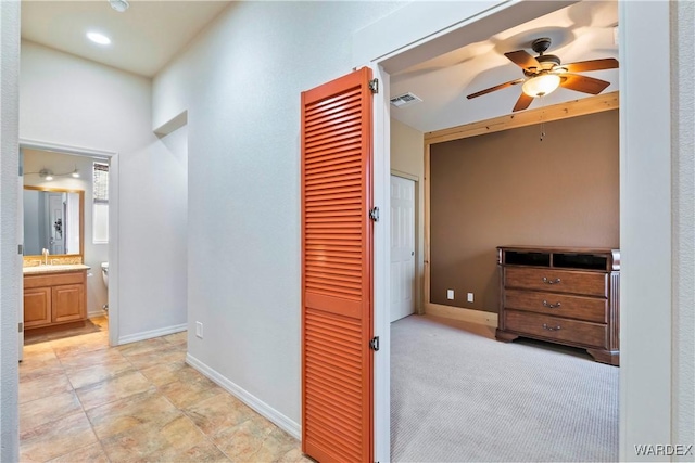 hallway with visible vents, a sink, and baseboards