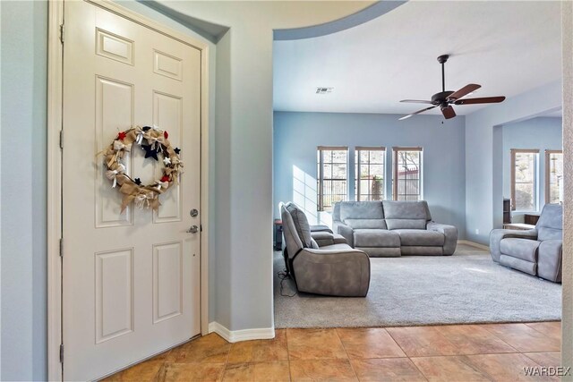 living room with light tile patterned floors, visible vents, baseboards, light colored carpet, and ceiling fan