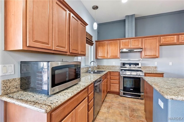 kitchen with brown cabinetry, appliances with stainless steel finishes, hanging light fixtures, under cabinet range hood, and a sink