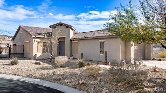 mediterranean / spanish home featuring concrete driveway, an attached garage, a tile roof, and stucco siding