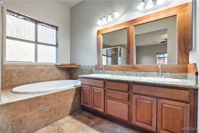 bathroom with double vanity, a stall shower, a garden tub, and a sink