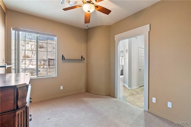 unfurnished office featuring a healthy amount of sunlight, light carpet, ceiling fan, and visible vents