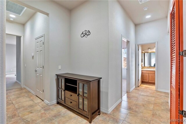 corridor with visible vents, a sink, and baseboards