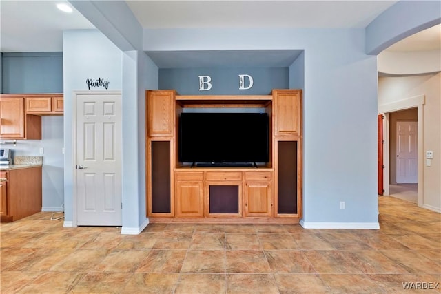 unfurnished living room featuring arched walkways and baseboards