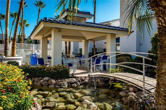 exterior space with stucco siding, fence, a garden pond, and a gazebo