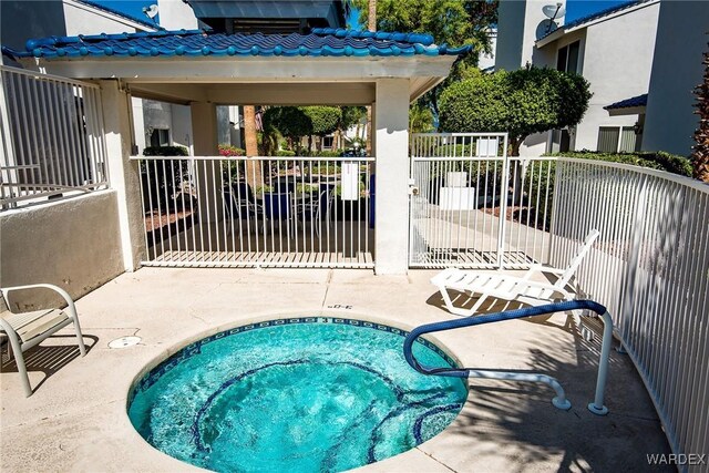 view of pool with a community hot tub, a patio area, and fence