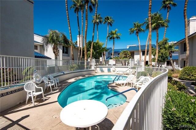 community pool with a patio area, fence, and a residential view