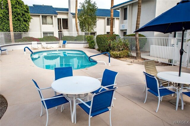 community pool featuring fence, outdoor dining area, and a patio