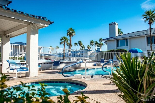 community pool featuring a community hot tub, a patio, and fence