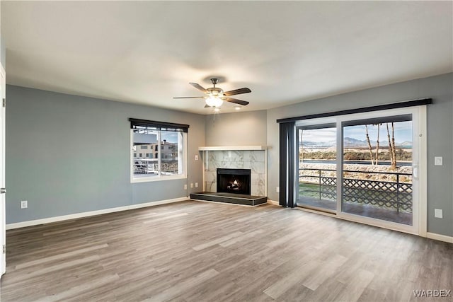 unfurnished living room with a healthy amount of sunlight, a fireplace, baseboards, and wood finished floors