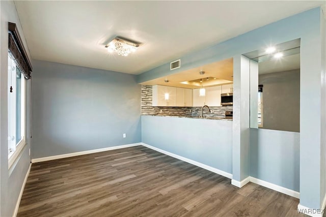 kitchen with baseboards, dark wood finished floors, visible vents, white cabinets, and stainless steel microwave