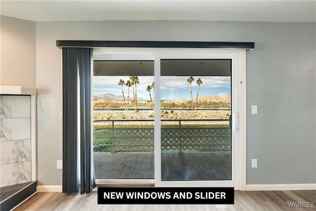 doorway featuring a healthy amount of sunlight, baseboards, and wood finished floors