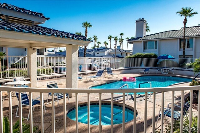 community pool with a patio, fence, a residential view, and a hot tub