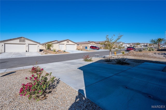 view of yard featuring driveway, an attached garage, and a residential view