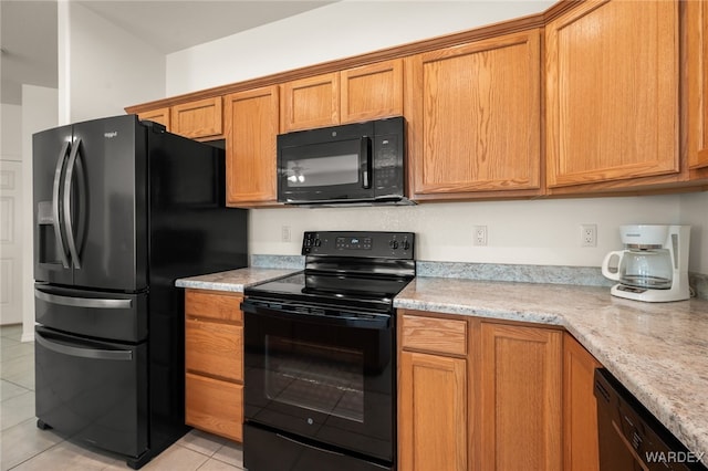 kitchen featuring light stone counters, brown cabinets, light tile patterned flooring, and black appliances