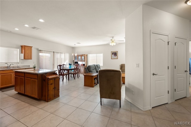 kitchen featuring visible vents, brown cabinetry, a center island, pendant lighting, and a sink