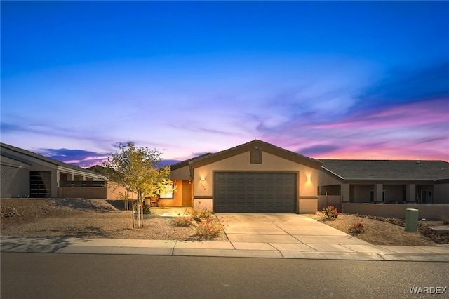 view of front of house with a garage, concrete driveway, and stucco siding