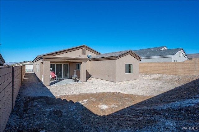 rear view of property featuring a fenced backyard, a patio, and stucco siding