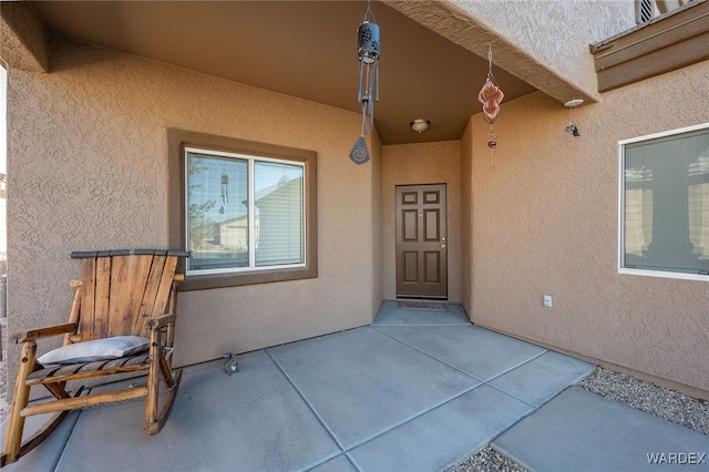 doorway to property featuring a patio area and stucco siding