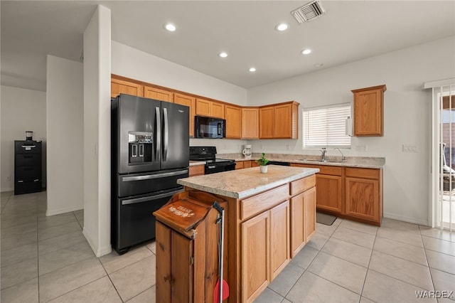 kitchen featuring light tile patterned floors, a kitchen island, visible vents, light countertops, and black appliances