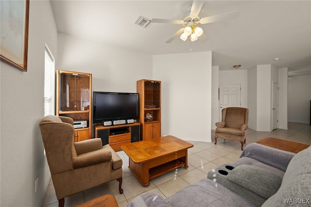 living area with light tile patterned floors, ceiling fan, visible vents, and baseboards