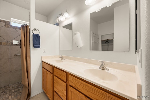 full bath with tiled shower, a sink, and double vanity