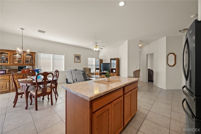 kitchen with pendant lighting, brown cabinets, freestanding refrigerator, open floor plan, and a kitchen island