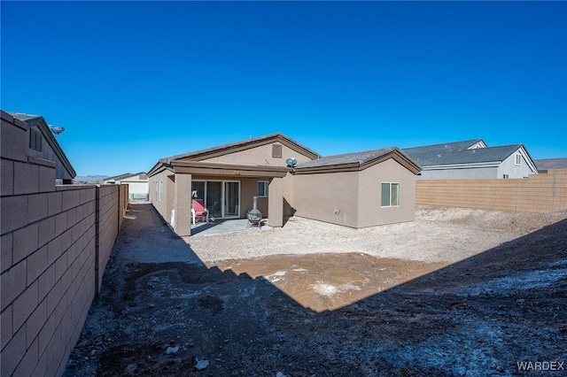 rear view of house featuring a fenced backyard, a patio, and stucco siding