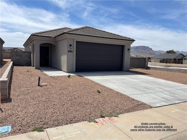 4939 N Famoso Dr, Kingman, AZ 86409 - view of front facade with concrete driveway, stucco siding, an attached garage, a tile roof, and a mountain view