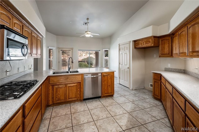 kitchen with stainless steel appliances, brown cabinetry, light countertops, and a sink