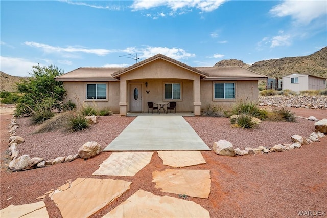 single story home with a patio, a tile roof, a mountain view, and stucco siding