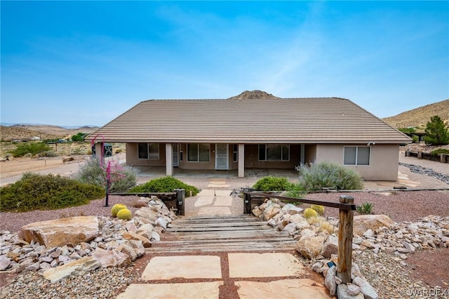 view of front of home with stucco siding, a mountain view, and a patio