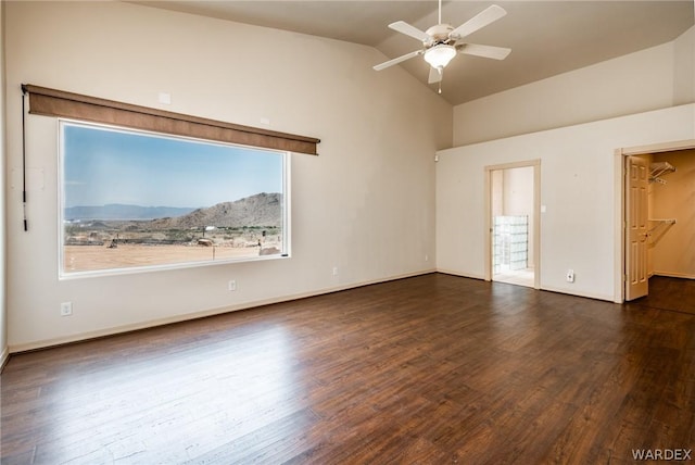 empty room featuring a ceiling fan, lofted ceiling, dark wood finished floors, and baseboards