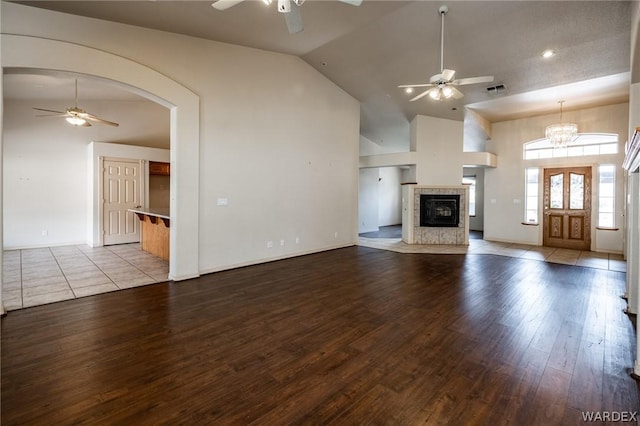 unfurnished living room with arched walkways, visible vents, light wood-style floors, ceiling fan, and high vaulted ceiling