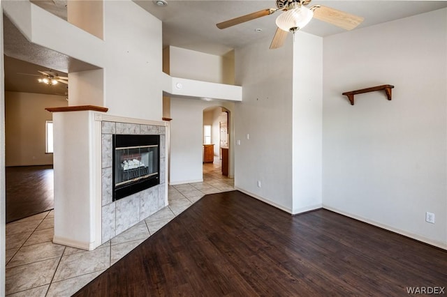 unfurnished living room with a ceiling fan, arched walkways, a fireplace, and light tile patterned floors