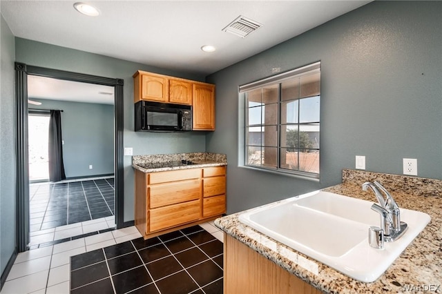 kitchen with visible vents, a sink, light stone countertops, dark tile patterned flooring, and black microwave