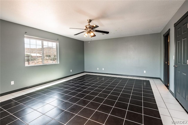 tiled empty room with a ceiling fan and baseboards