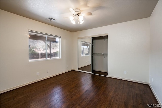 unfurnished bedroom with dark wood finished floors, a closet, visible vents, ceiling fan, and baseboards