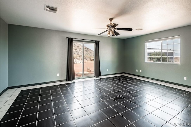 tiled spare room with baseboards, a textured ceiling, visible vents, and a ceiling fan